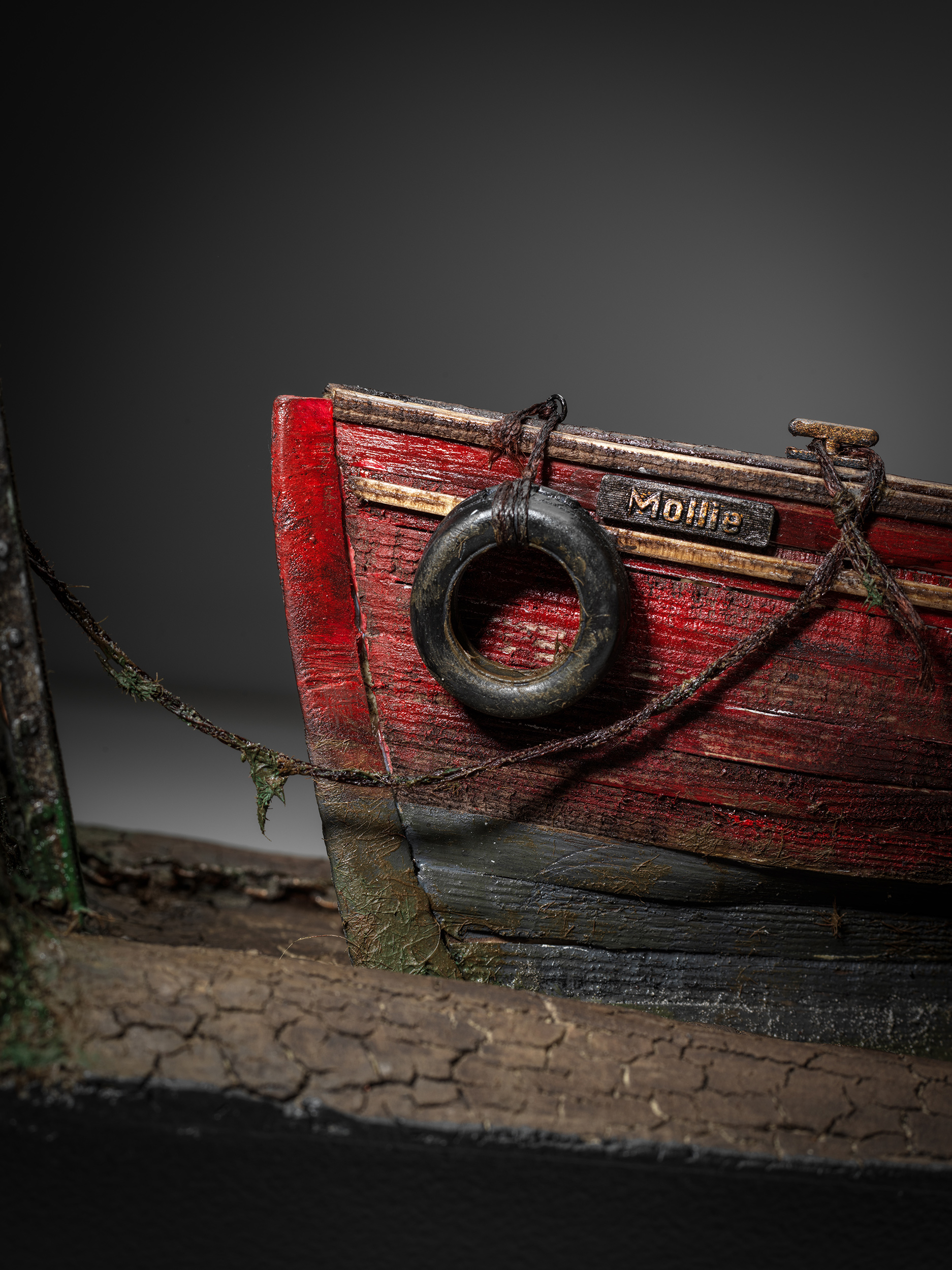 Mollie's name board, red timber hull and weathered tyre fender